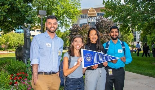 students posing with MWU flag outside